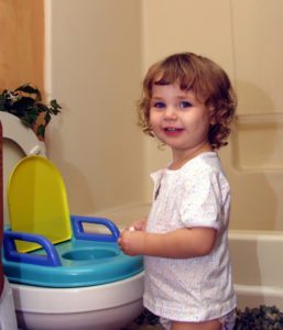 toddler smiling next to her potty seat