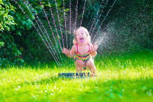 Little Girl Playing With Garden Water Sprinkler