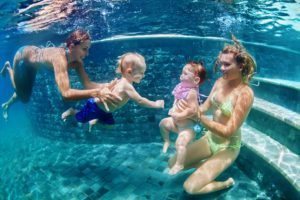 Mothers With Children Swim Underwater In Blue Beach Pool